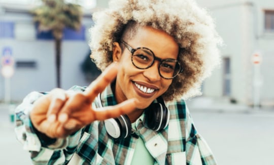 woman doing peace sign with curly hair and glasses