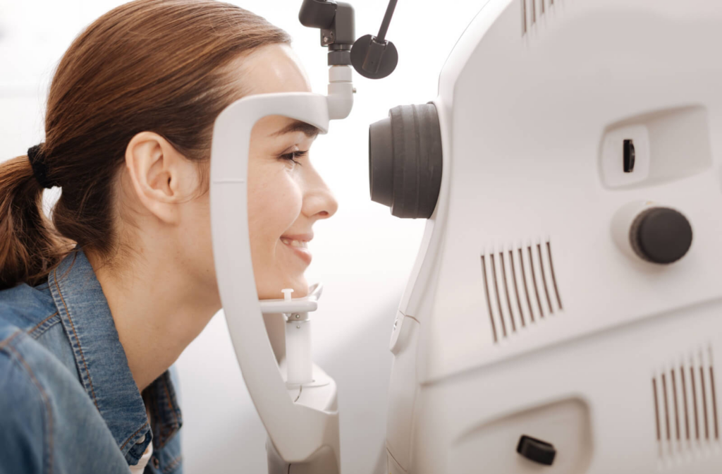 A woman sitting in an optometrist's office looking into a machine that tests her vision.